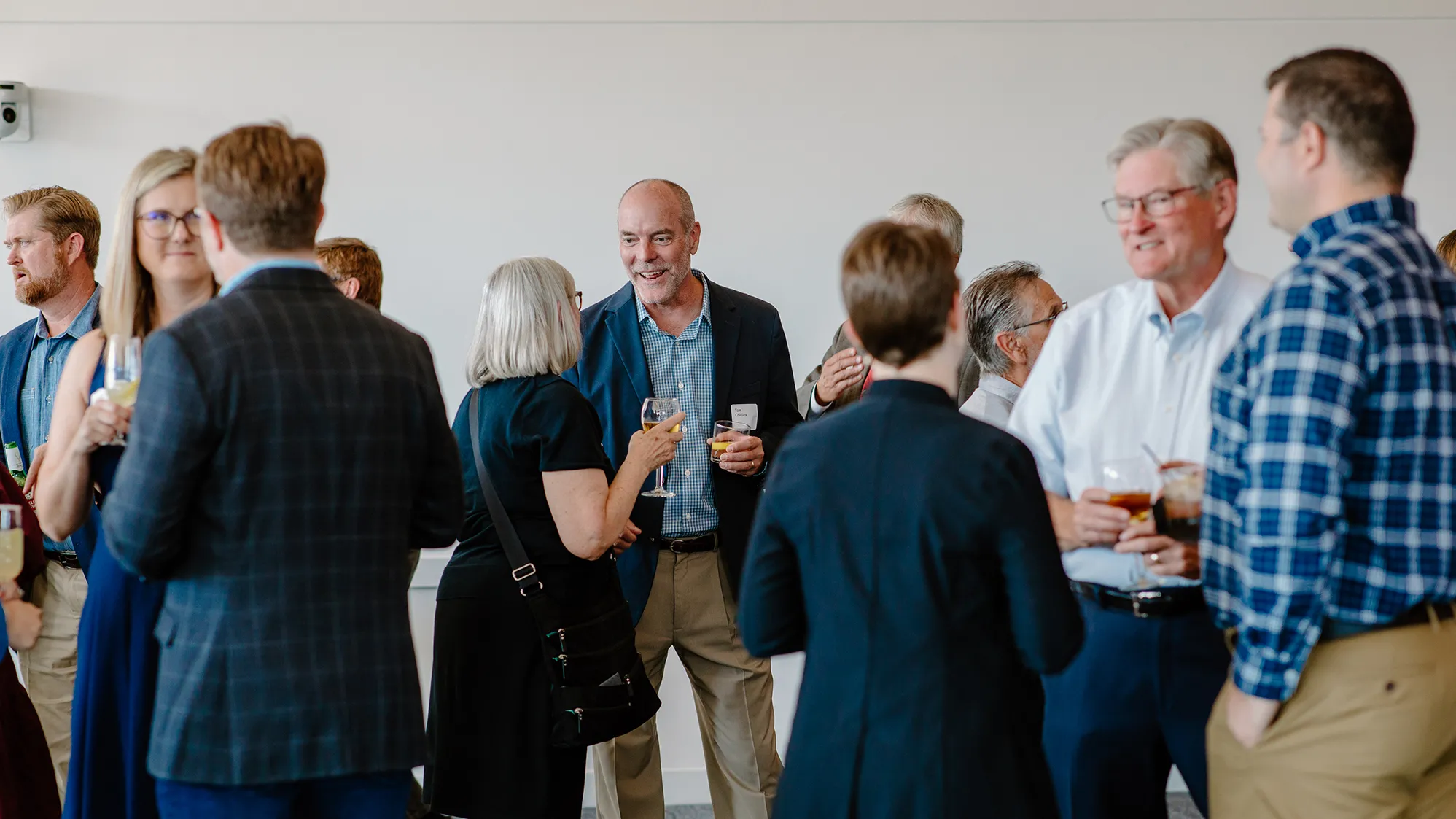 Group of people standing and talking at the DesignGroup 50th anniversary event.