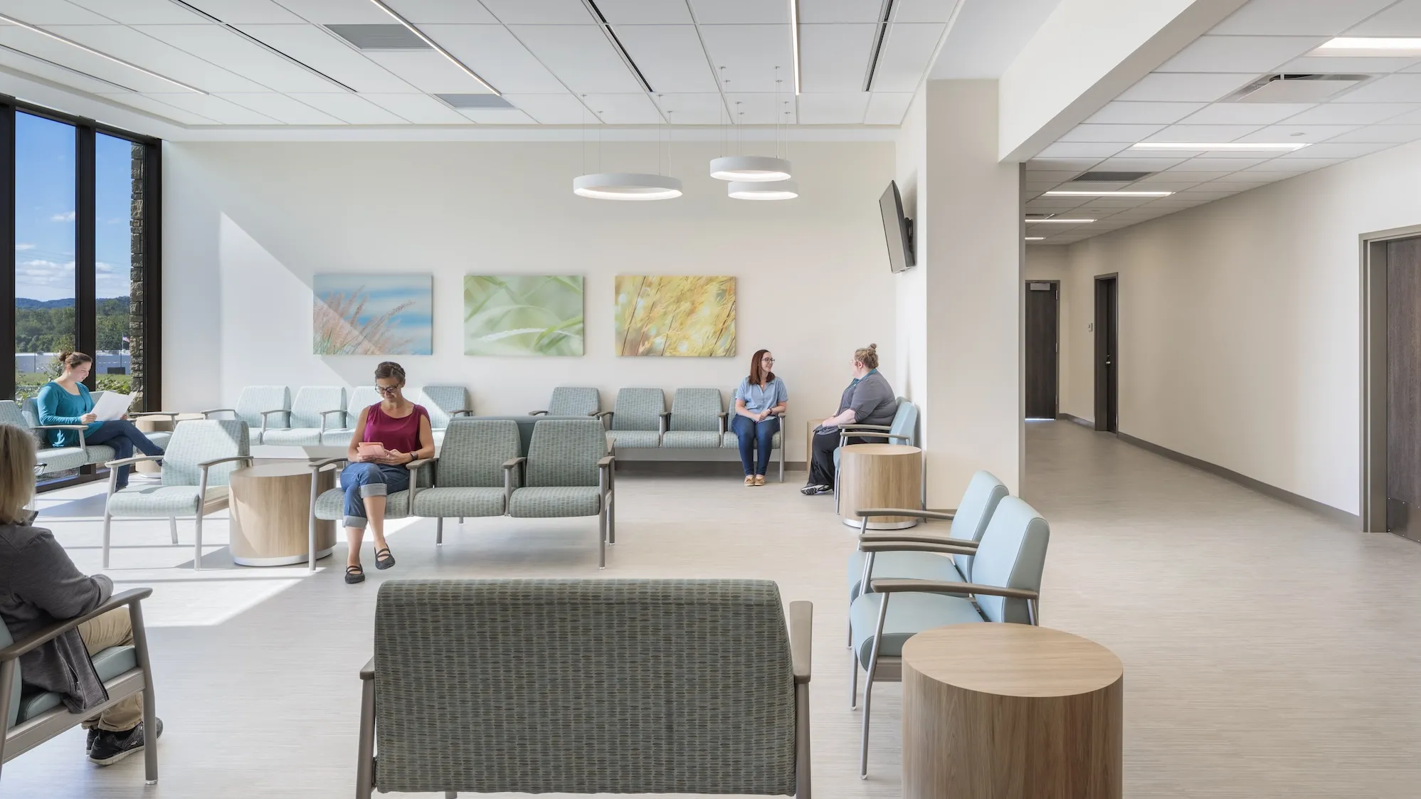 Interior waiting room during the day with various people sitting