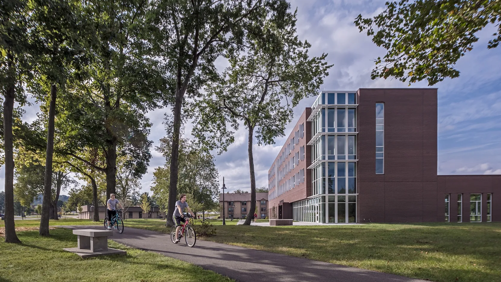 Exterior landscape of McConnell Residence Hall while two student ride past the building on their bikes