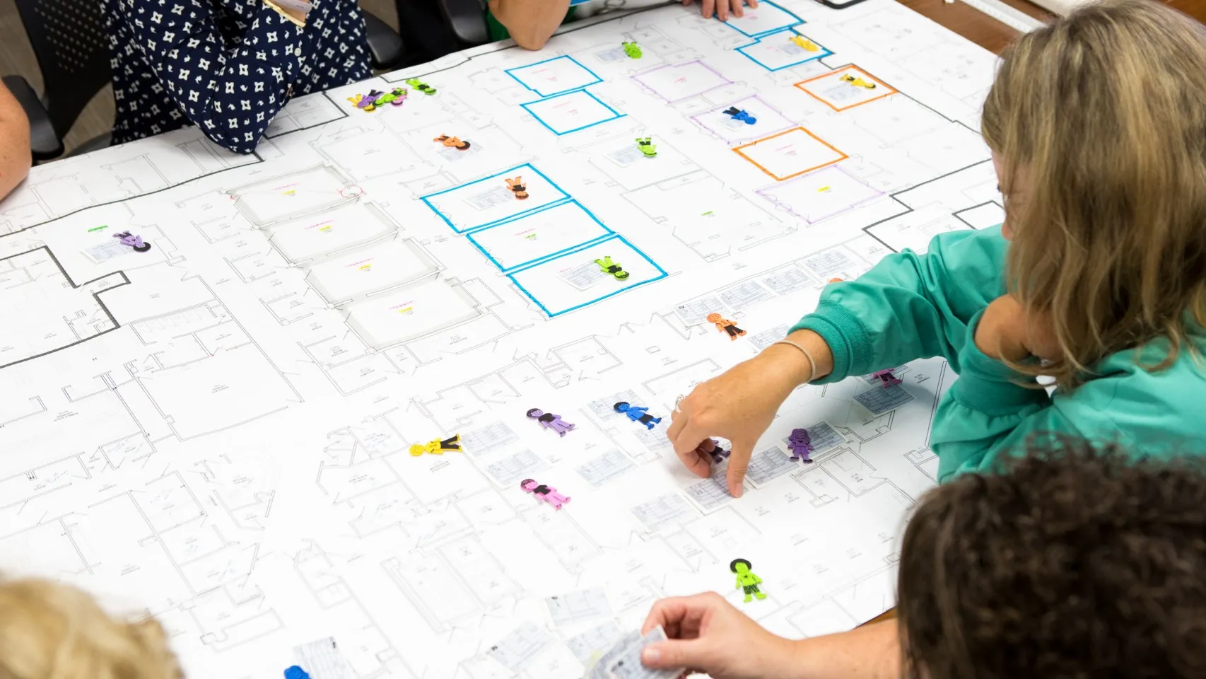 A planning session with clinical staff surround the blue prints a hospital