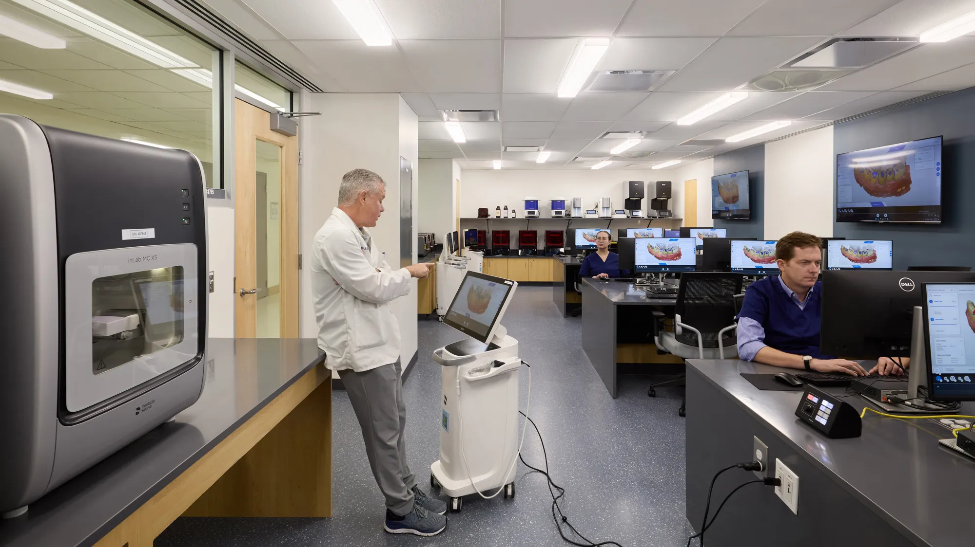 professor wearing lab coat in classroom with computers and dental equipment