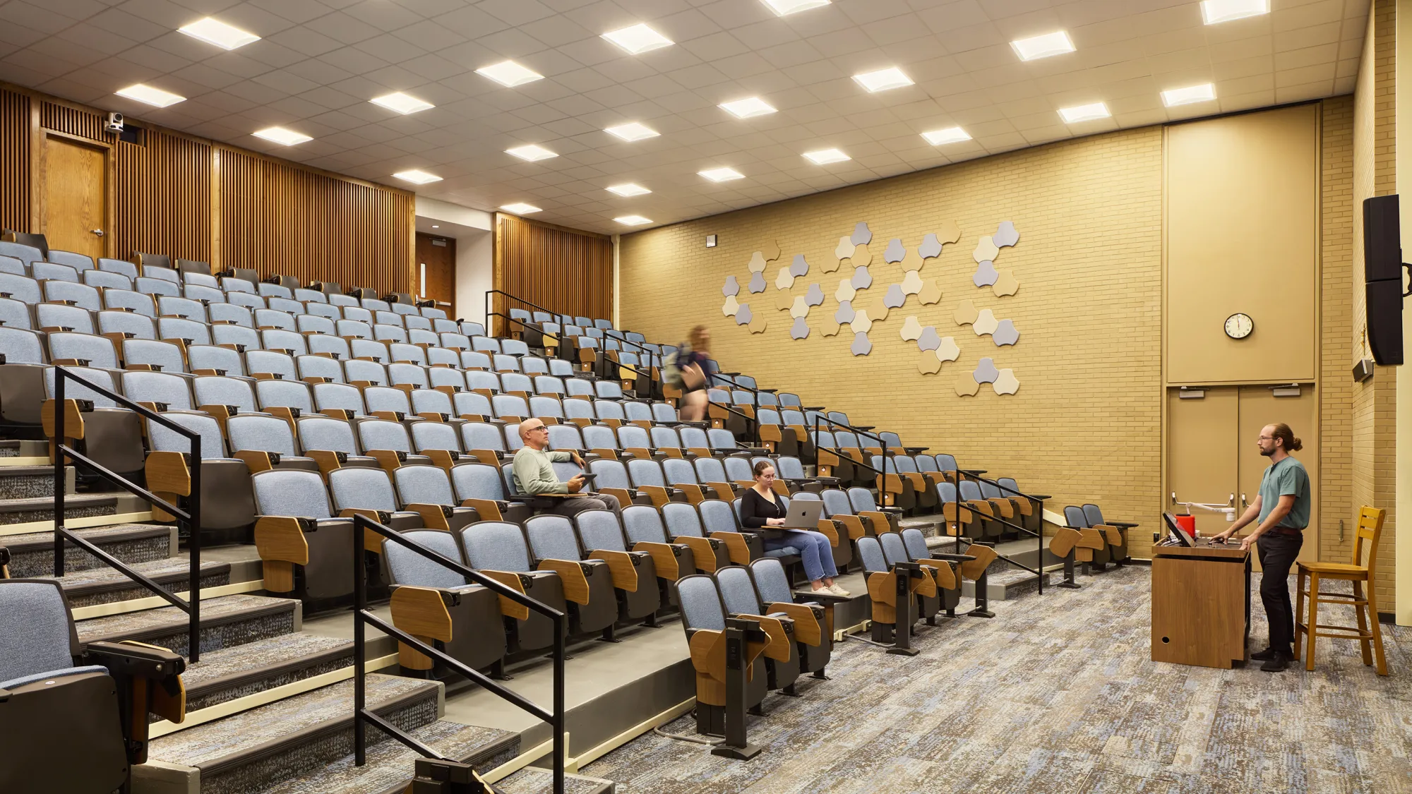 amphitheater-style lecture hall with blue upholstered seats and acoustic paneling