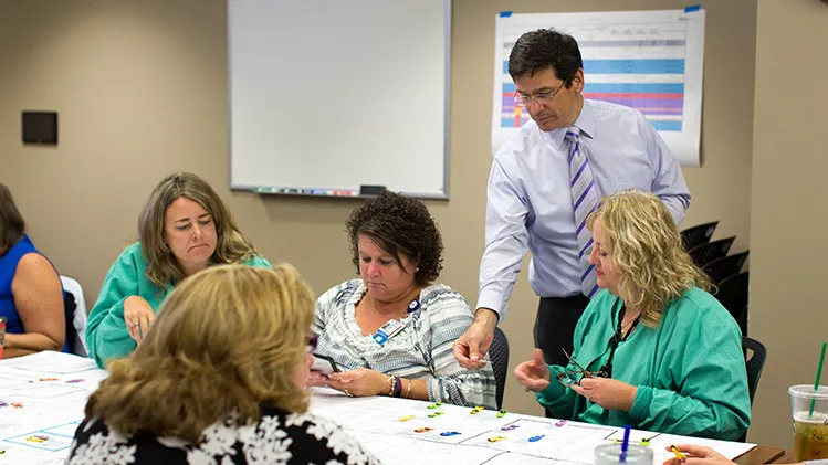 Sherm Moreland performing a simulation experience with a group of people seated at a table.