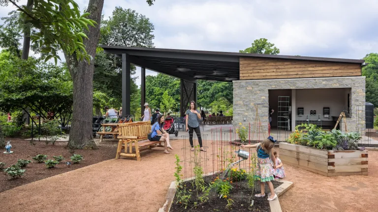 Outdoor space featuring mulch gardens with children watering the plants