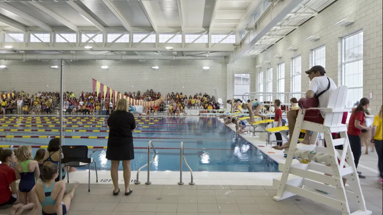 Interior pool during a swimming race event, the swimmers about to dive into the pool