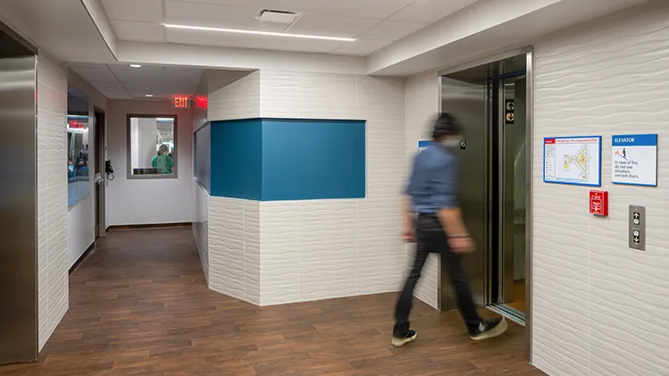 Hallway of a hospital with a person walking into an elevator