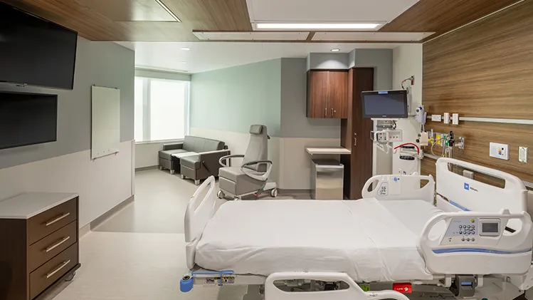 Hospital patient room with warm wood paneling on wall and ceiling