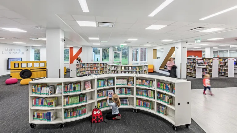 Interior of Hilliard Library children's section featuring a child interacting with books on a curved bookshelf