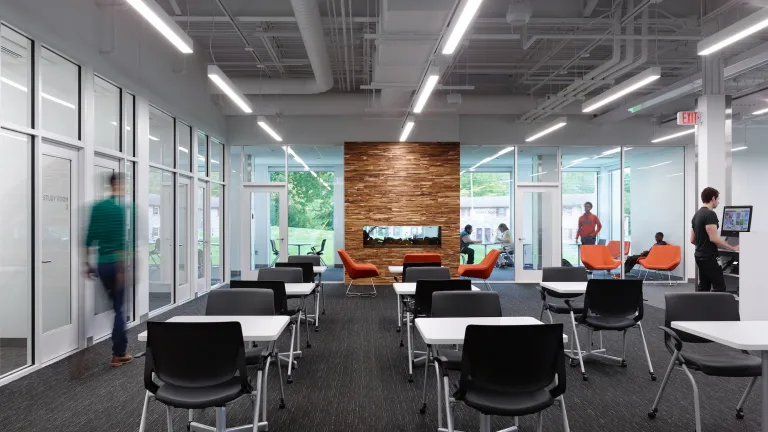 Interior day of the Northern Lights Columbus Library study space made up of multiple two person tables and a modern fireplace in the background