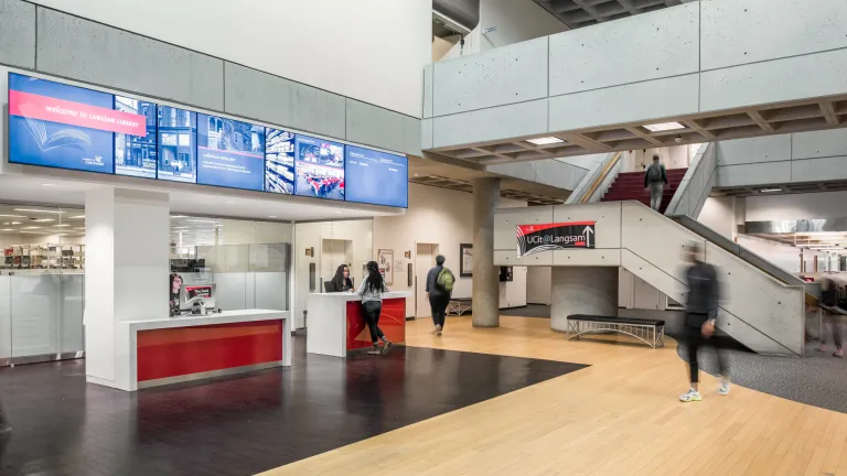 Interior of Langsam library entrance featuring check in desk and cement stair case to second floor