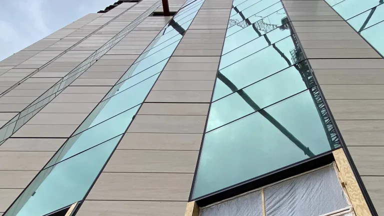 Close up of exterior of a building's paneled windows and wall in construction