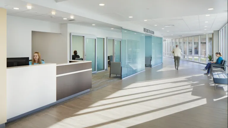 Hallway space of Mercer Health featuring a registration desk with blue tinted glass walls