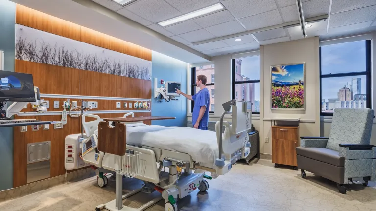 Mercy Hospital patient room featuring large windows, dark wood paneling and light blue walls