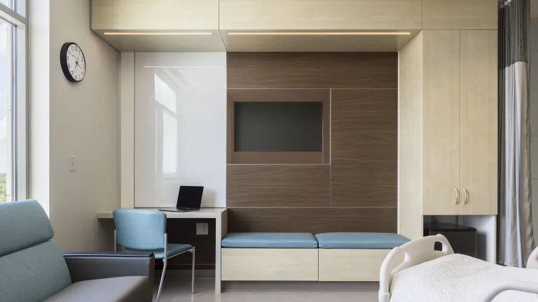 Inpatient room with light teal accents and light maple wood paneling