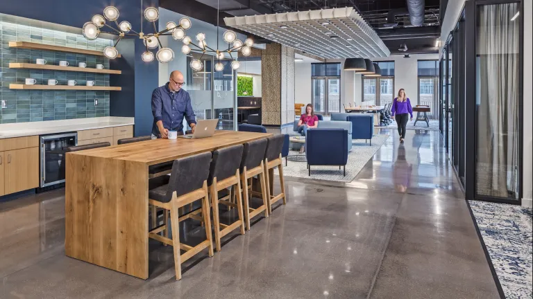 Kitchenette or coffee bar space in a mixed use work space, cement floors, raw wood table, blue accented walls