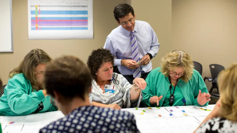 Sherm Moreland interacting with clinical staff at a table with a blueprint