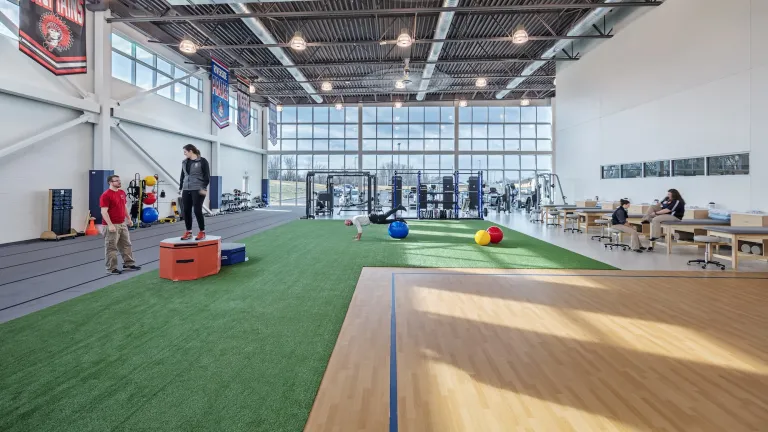 Interior of Mary Rutan's health center, featuring green turf space, wooden court area and exercise equipment