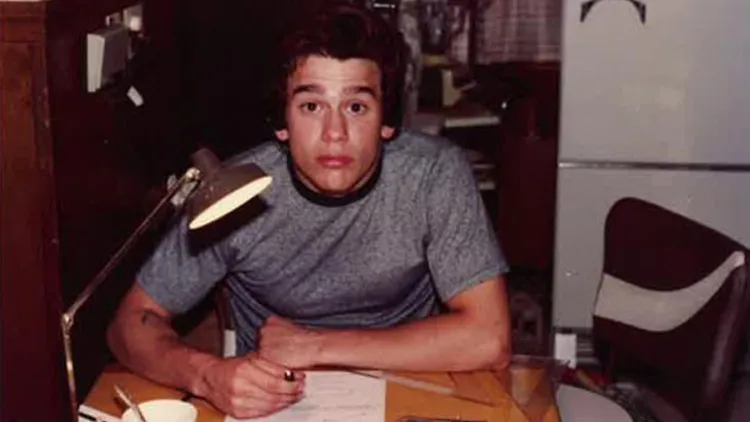 Boy sitting at table writing in notebook