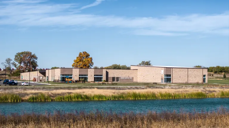 tan brick building with large pond in foreground
