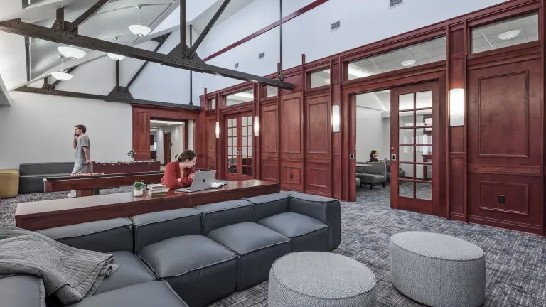 student common space with vaulted ceiling, wood panelling, and lounge seating