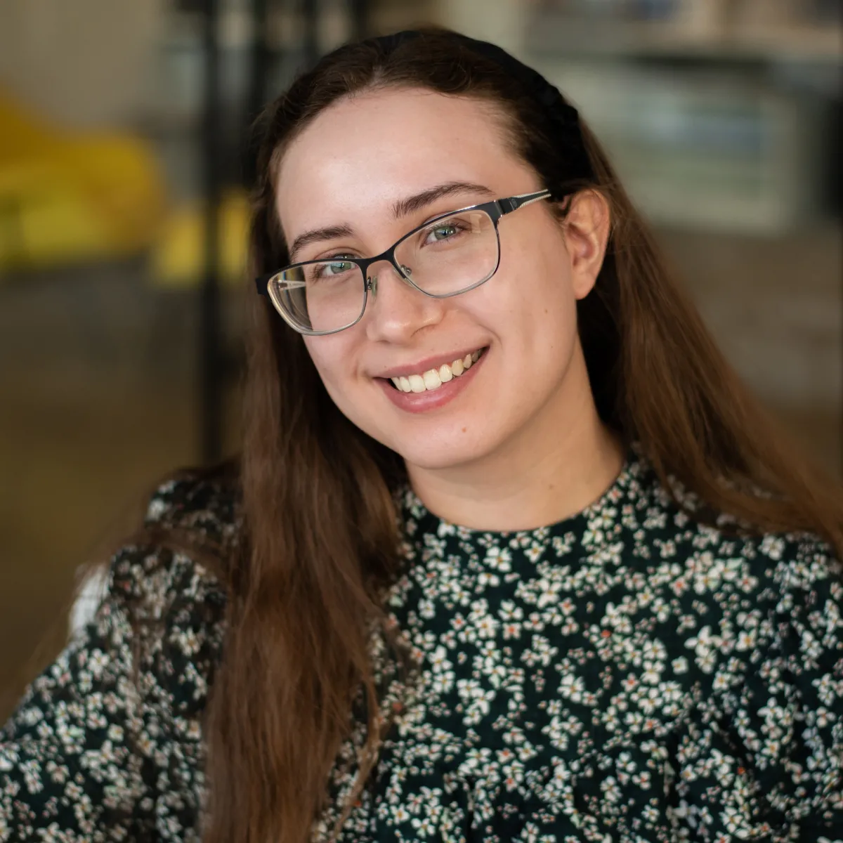 Abby Blend smiling, wearing a floral green and black blouse