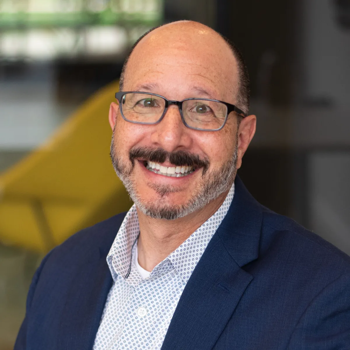 Alan Schlossberg smiling while wearing a navy blazer and blue shirt