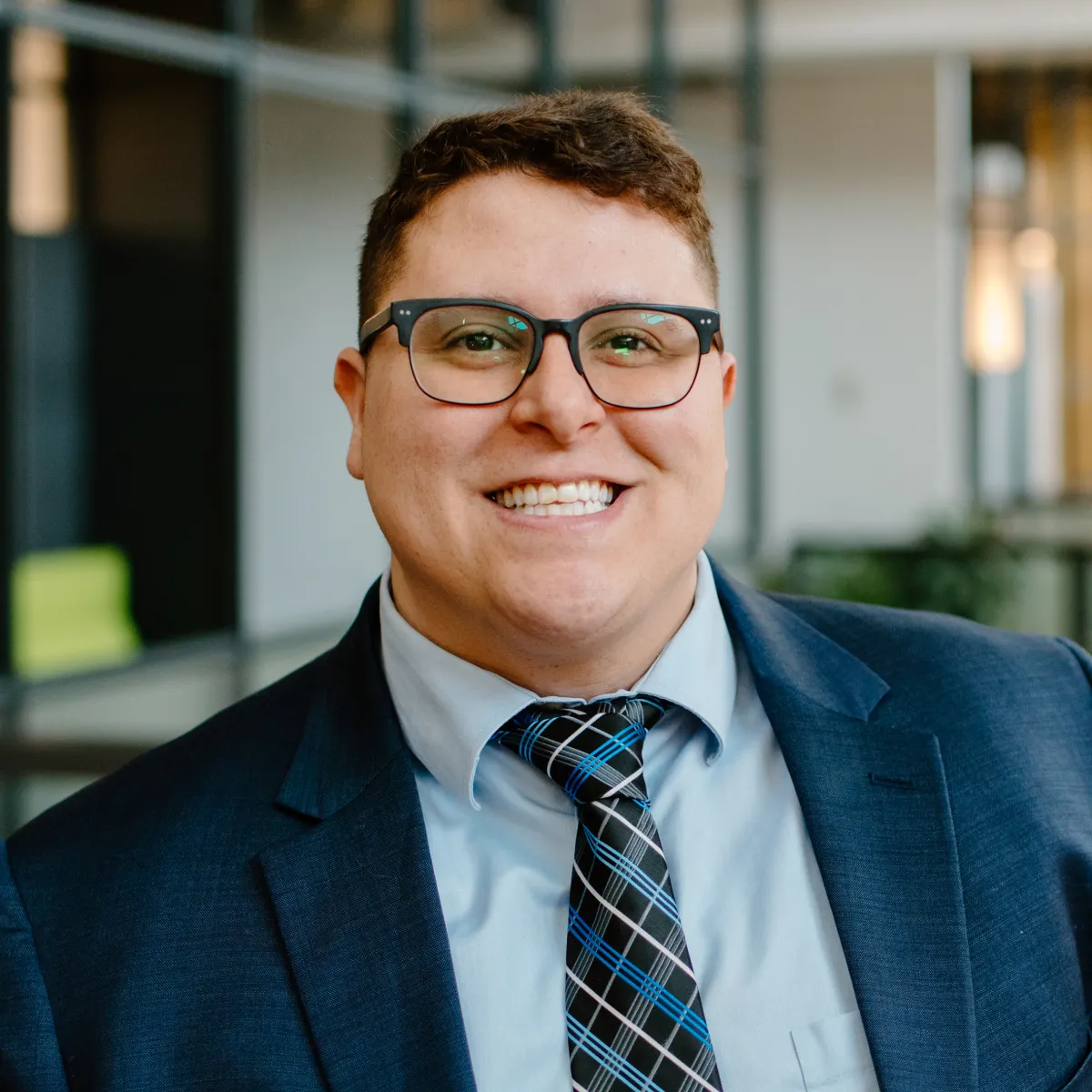 David Morales smiling, wearing a blue blazer and teal gingham tie