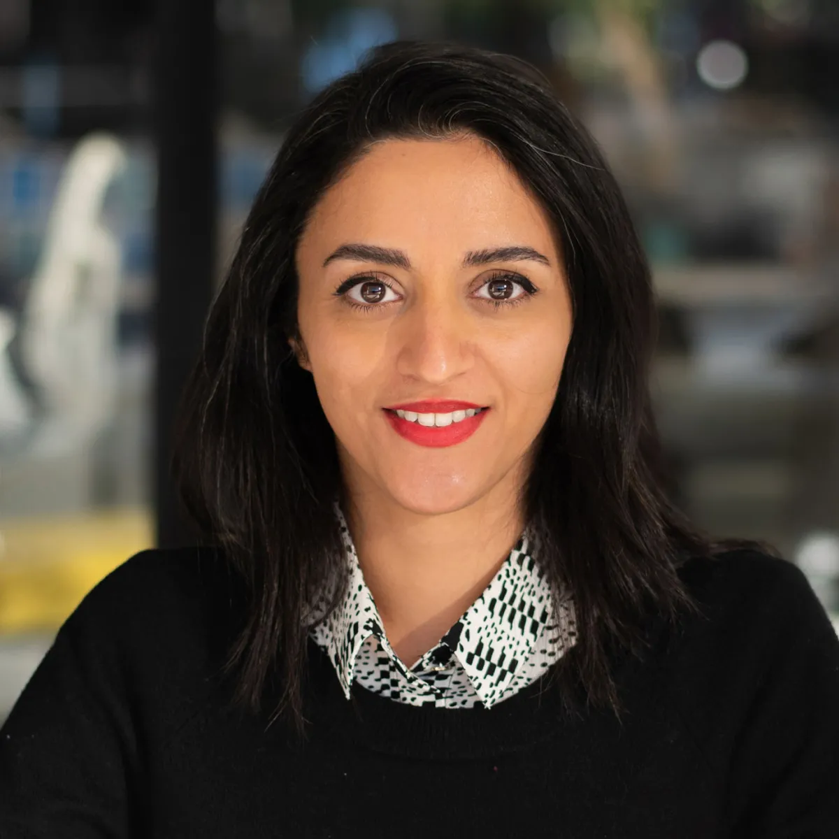 Parva Markiw smiling, wearing a black sweater with grey button down underneath