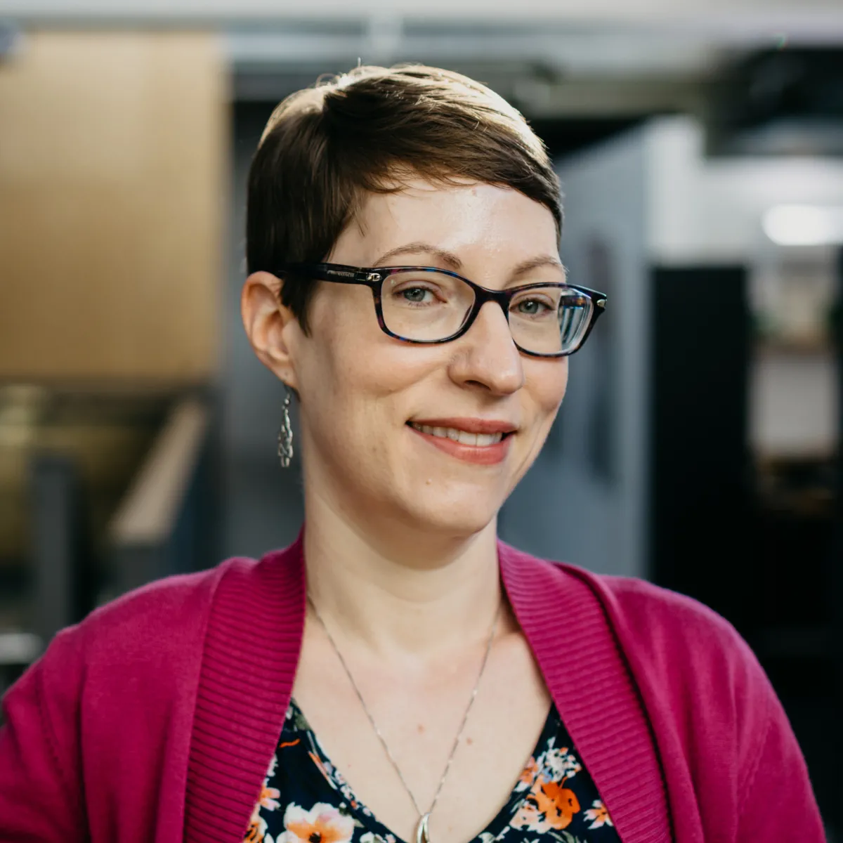 Shara Vross smiling, wearing a magenta sweater with floral blouse