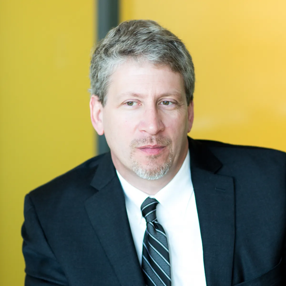 Tom Gerken looking off camera, wearing a black blazer