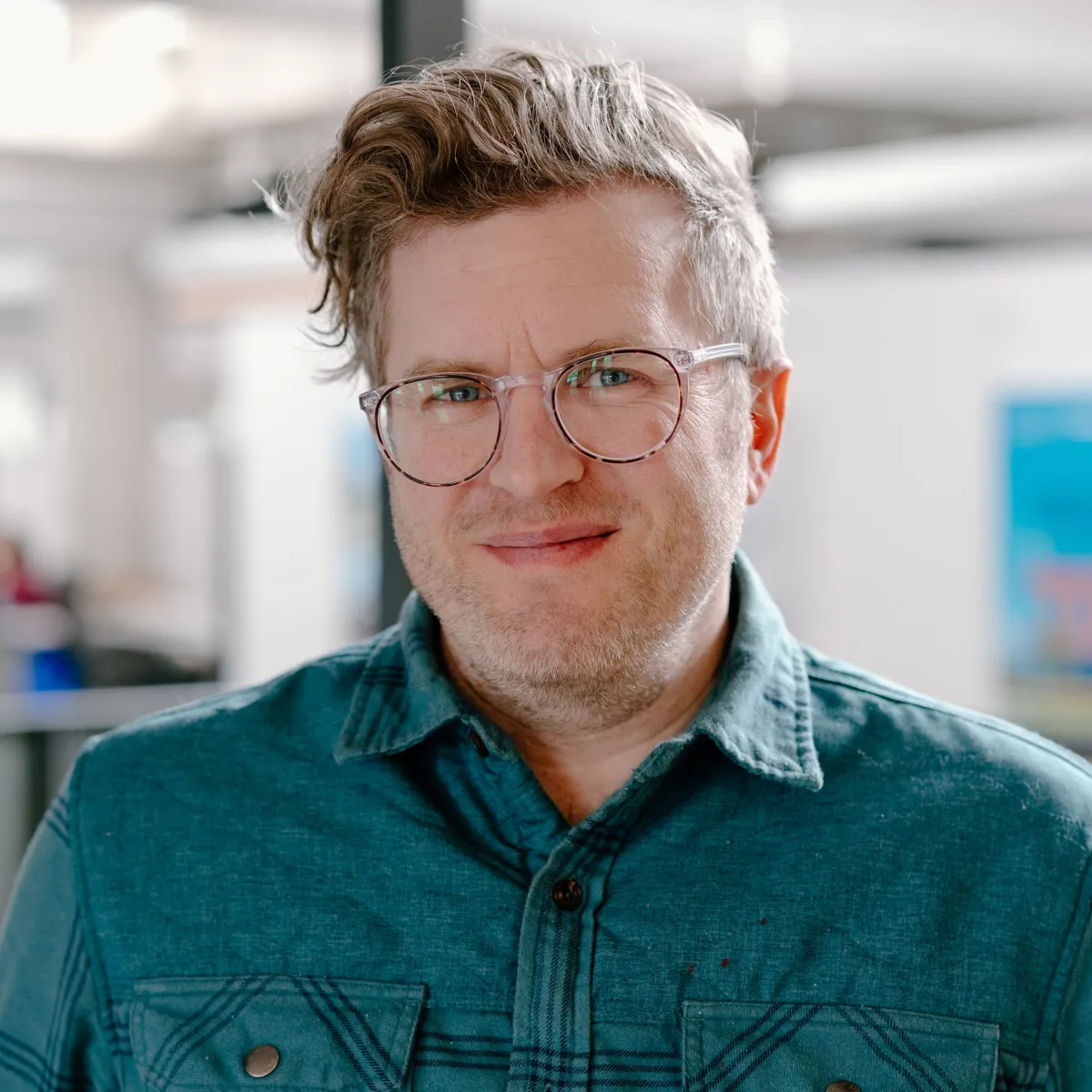 man with glasses wearing a teal shirt