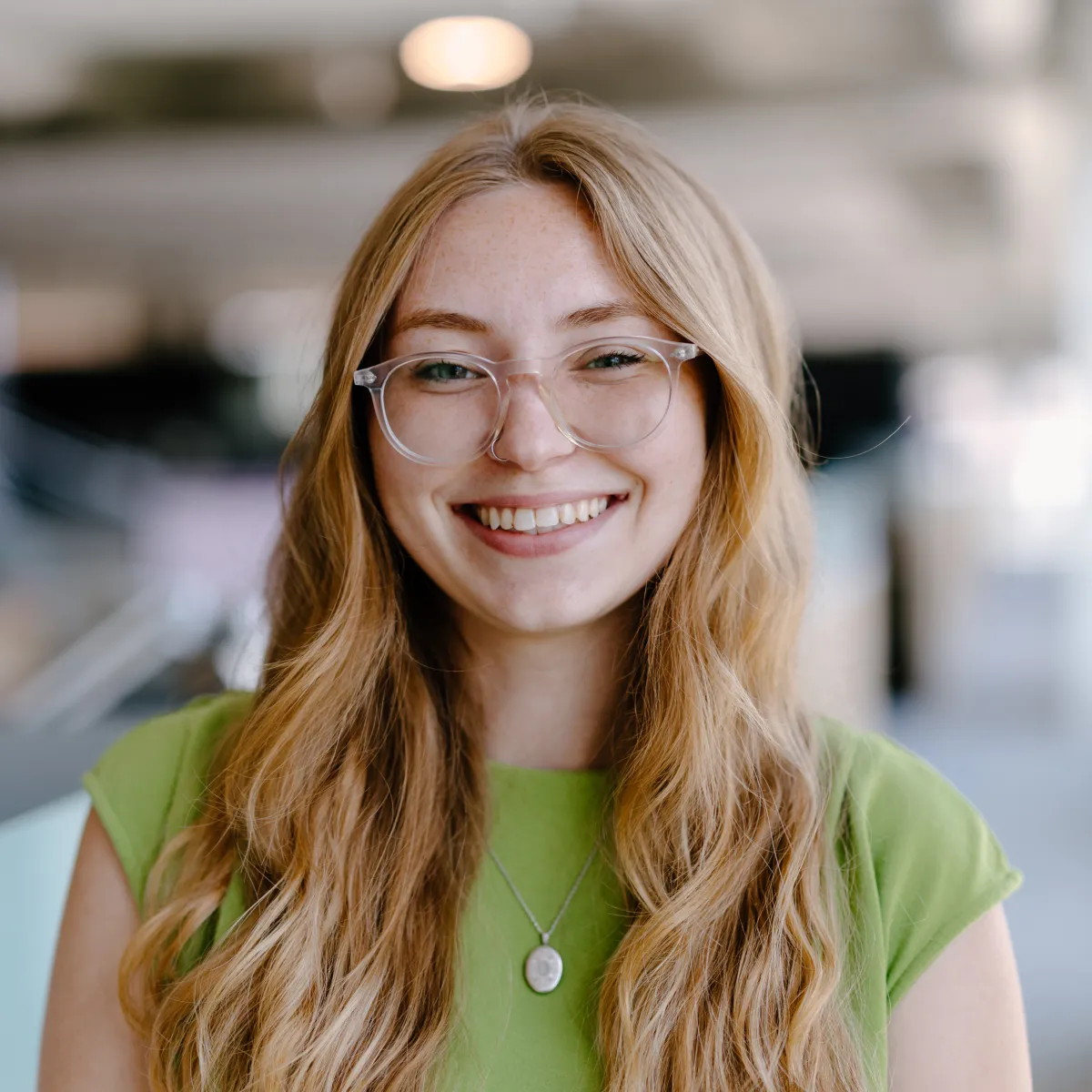 woman with long wavy hair wearing glasses and green shirt