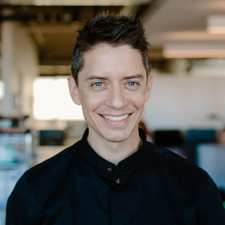 Daniel Mathur smiling, wearing a black button down shirt