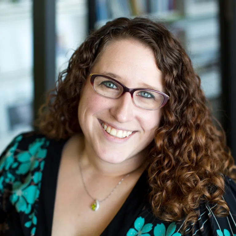 Sarah Eversman smiling, wearing a teal and black floral blouse