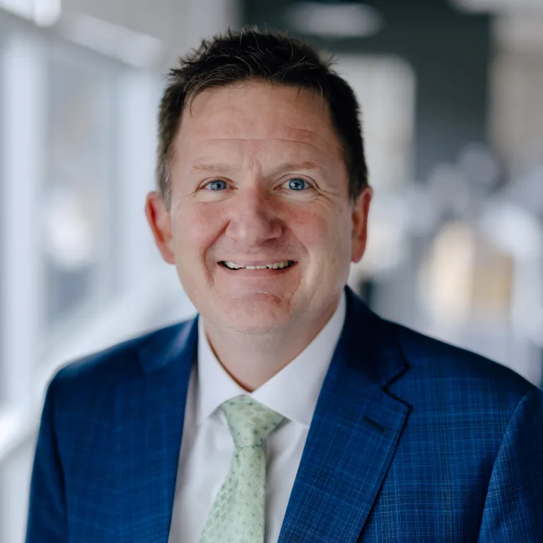 smiling man in blue sports coat and pale green tie