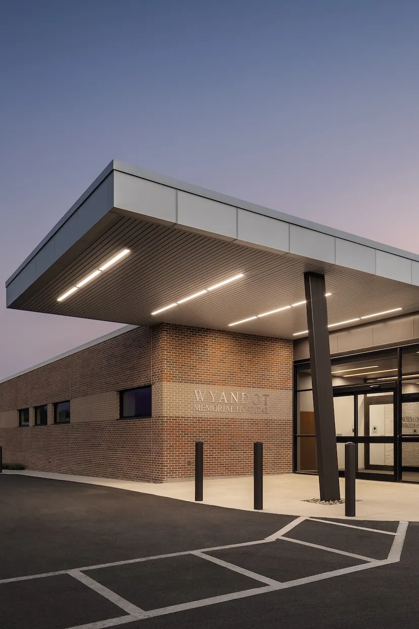 Exterior entrance of Wyandot Memorial Hospital at dusk, one story building featuring brick walls and floor to ceiling windows