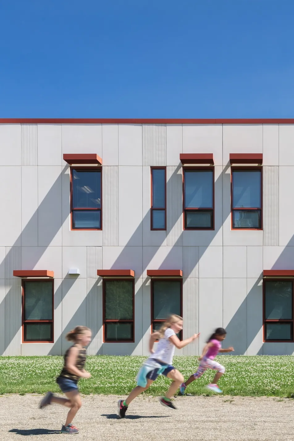 Children running against the facade of the Columbus Spanish Immersion Academy