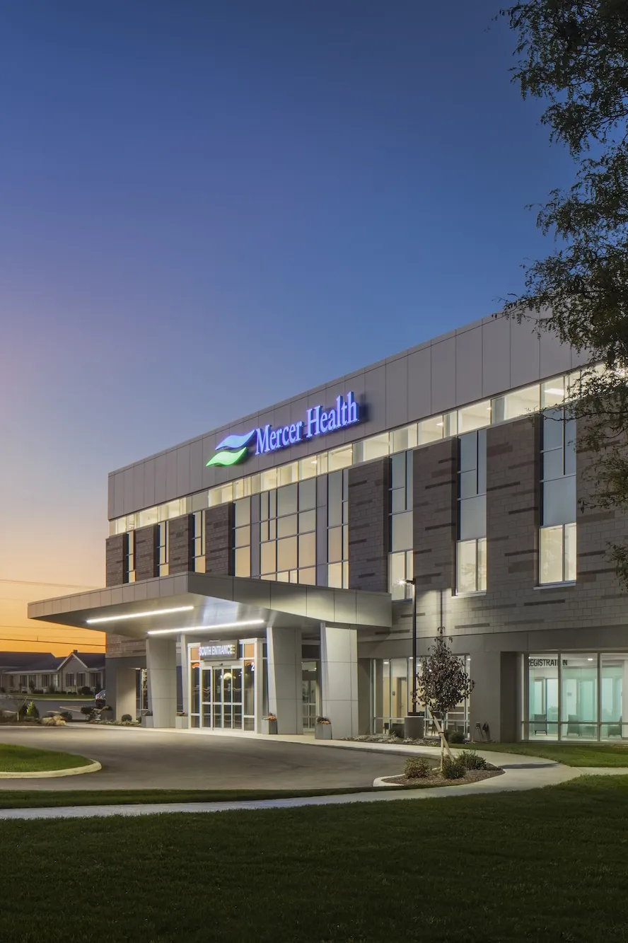 Exterior of Mercer Health in the evening, a modern building with mixed bricks and floor to ceiling windows, multi story building