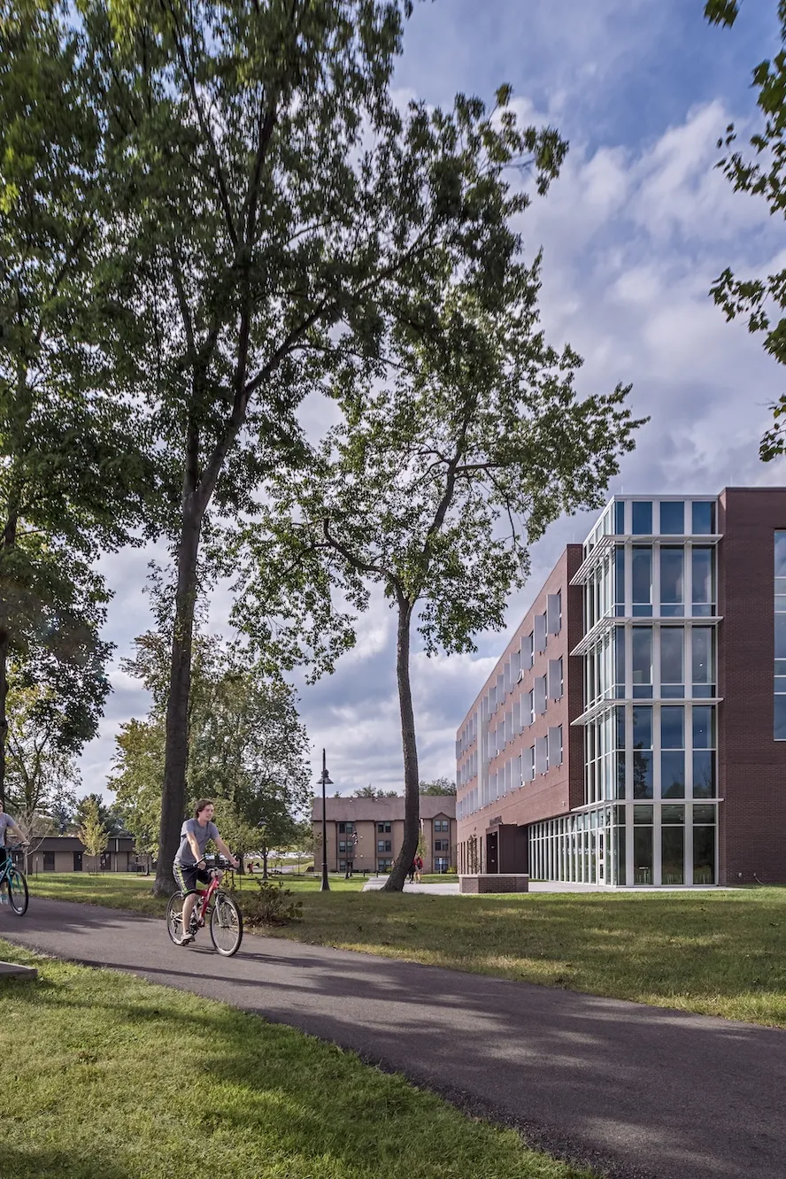 Exterior landscape of McConnell Residence Hall while two student ride past the building on their bikes