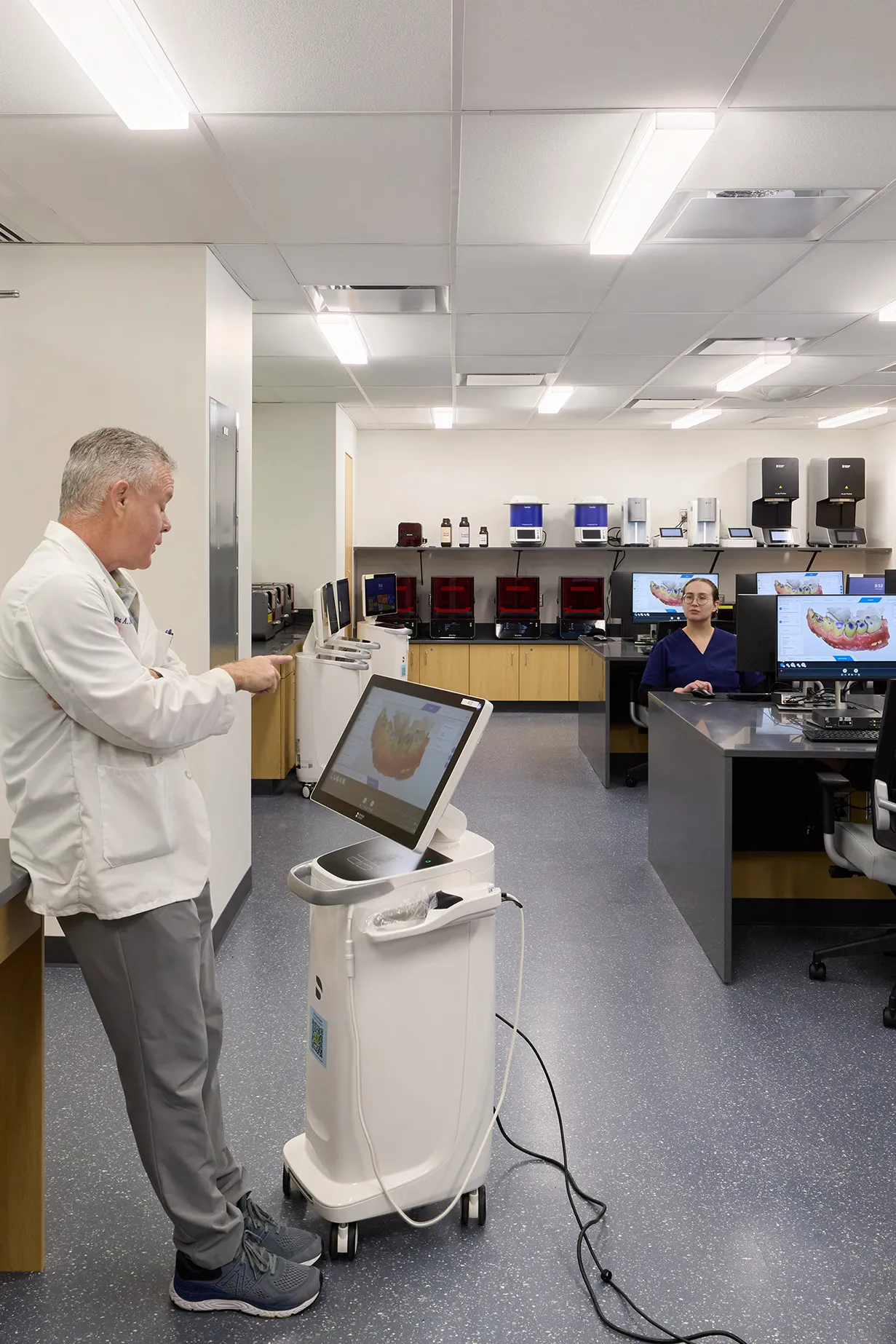 professor wearing lab coat in classroom with computers and dental equipment