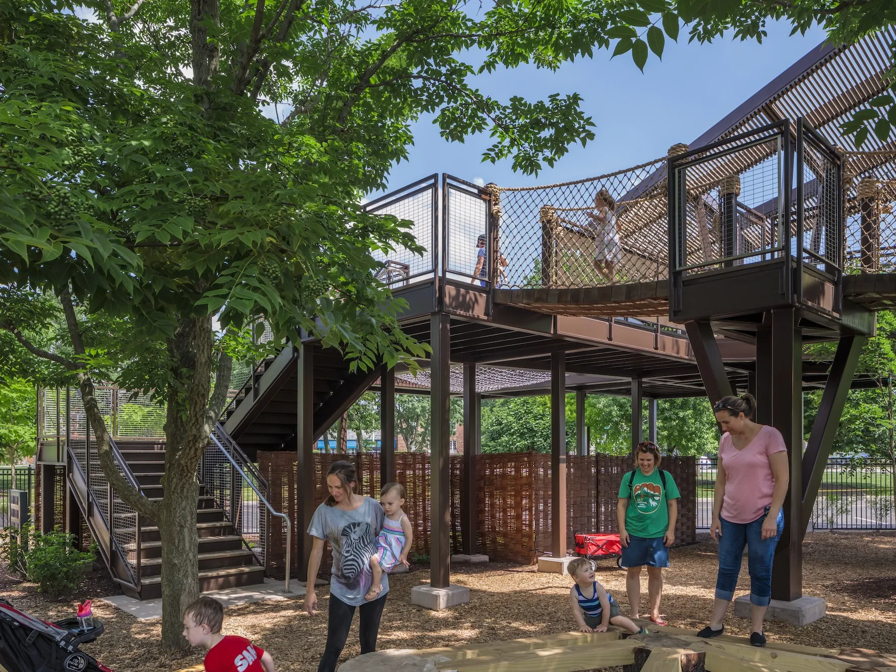 Outdoor play space with canopy jungle gym featuring rope bridge