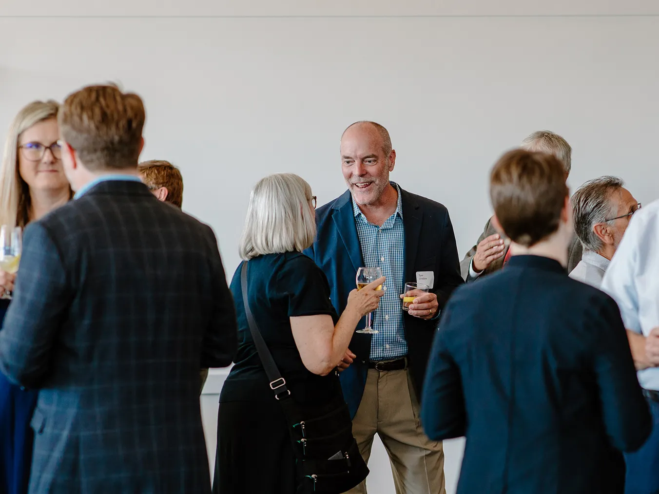 Group of people standing and talking at the DesignGroup 50th anniversary event.