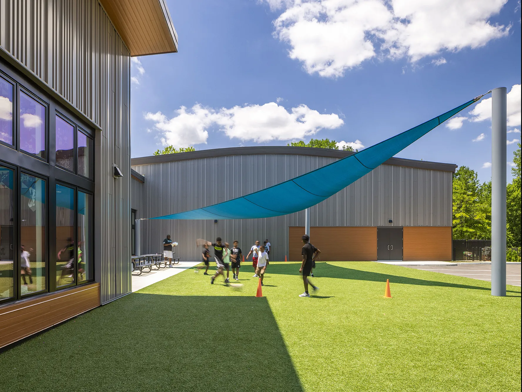 Children playing soccer outside in a partially shaded courtyard.