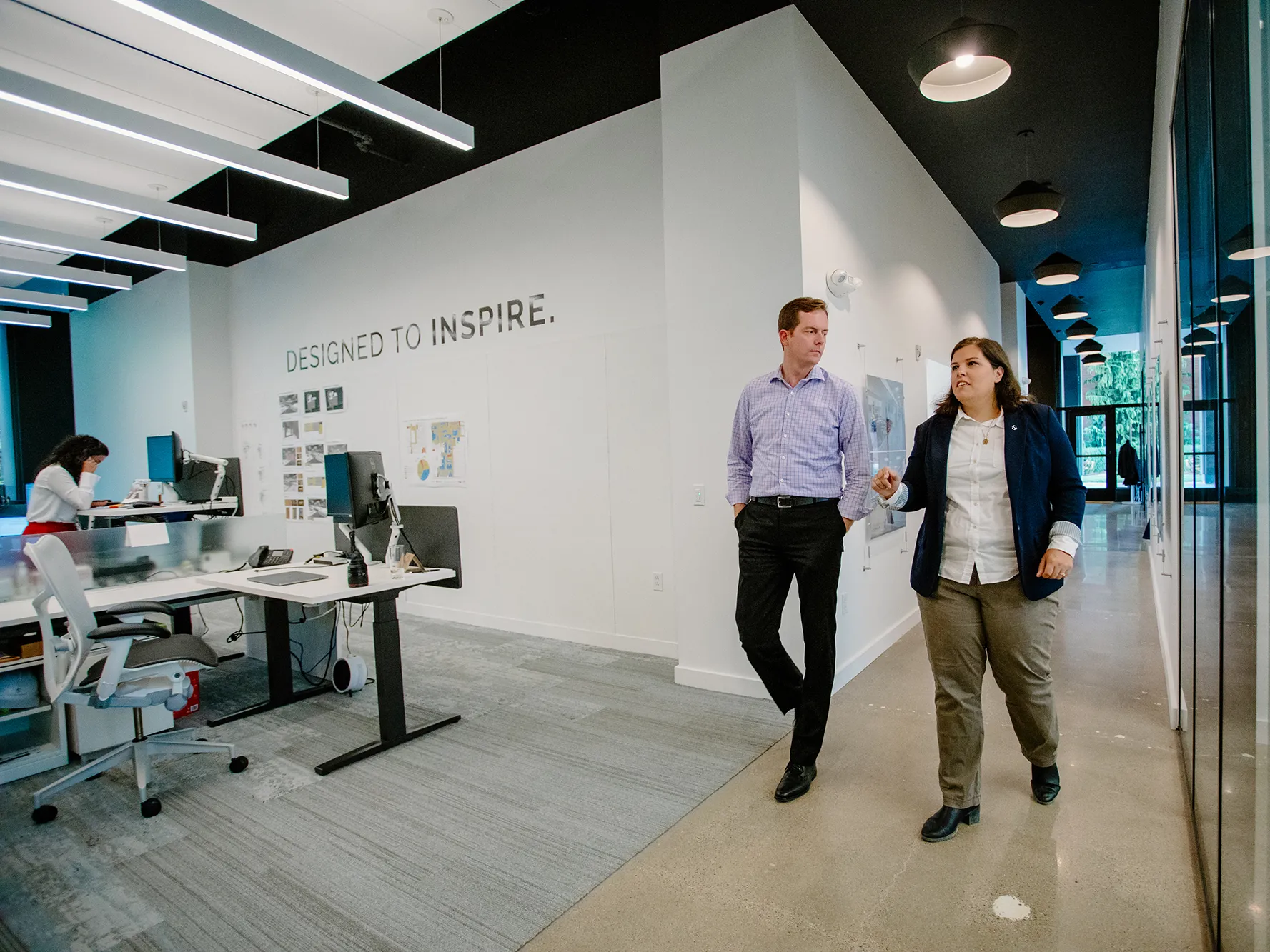 Two people walking down the corridor of the Pittsburgh DesignGroup office.