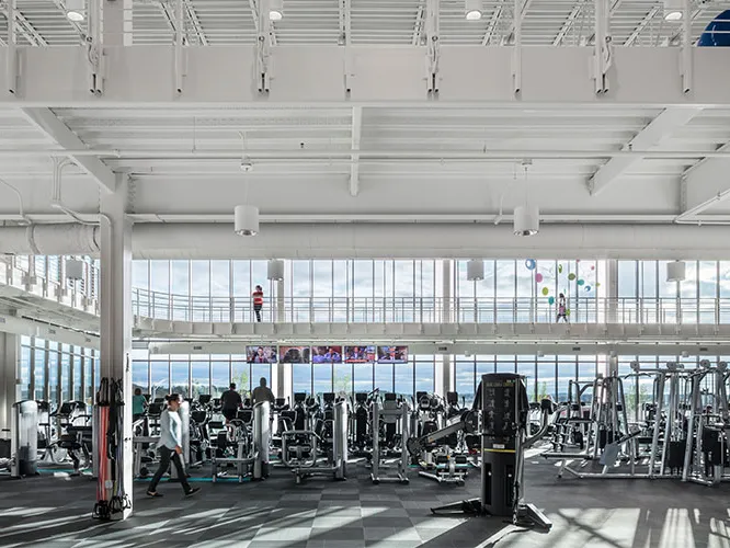 Interior of a YMCA fitness space with variety of workout equipment and floor to ceiling windows