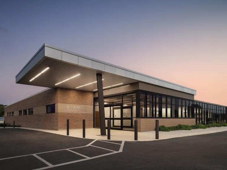 Exterior entrance of Wyandot Memorial Hospital at dusk, one story building featuring brick walls and floor to ceiling windows