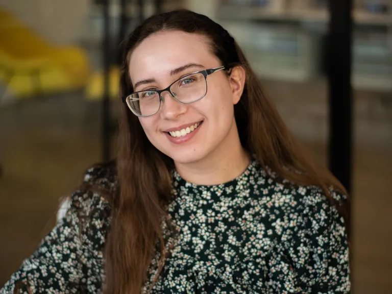 Abby Blend smiling, wearing a floral green and black blouse