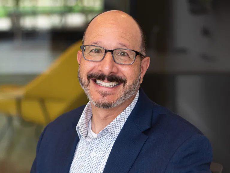 Alan Schlossberg smiling while wearing a navy blazer and blue shirt