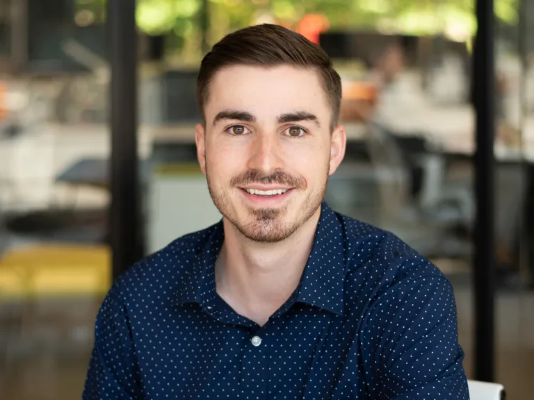 Alex Keiser smiling, wearing a navy polka dot button down shirt