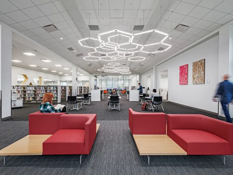 Interior of Hilliard Library featuring two red couch seating areas and hexagonal ceiling lights